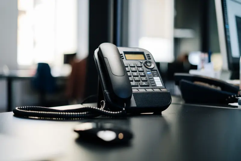 A black desk phone next to the users computer